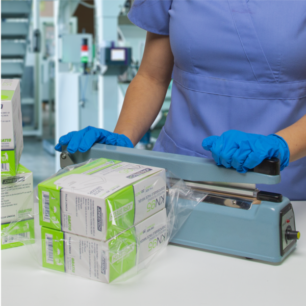 Entorno médico. Una enfermera está sellando una bolsa sellable con dos cajas de mascarillas usando la selladora por impulso manual de 12 pulgadas