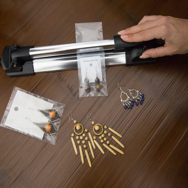 Vista superior de una selladora térmica manual por impulso utilizada para sellar una bolsa sellable con joyería artesanal en su interior