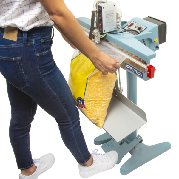 Una mujer sellando una bolsa de plástico extragrande con maíz dentro.