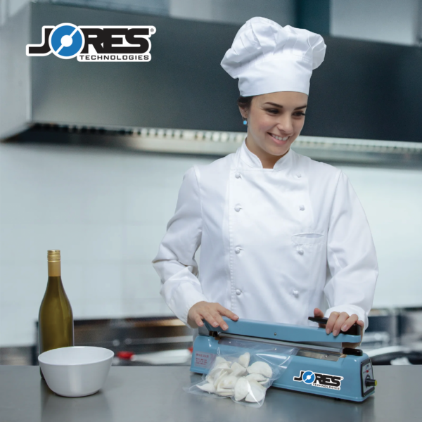 Joven chef en una cocina industrial sellando una bolsa sellable de dumplings con la selladora manual de impulso para bolsas JORES TECHNOLOGIES® de 16 pulgadas.