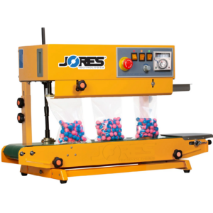 Selladora continua de banda JORES TECHNOLOGIES® amarilla sellando bolsas con bolas de pintura azules y rosas. La máquina selladora de bolsas está en posición vertical y las bolsas sellables permanecen de pie sobre el transportador mientras se sellan.