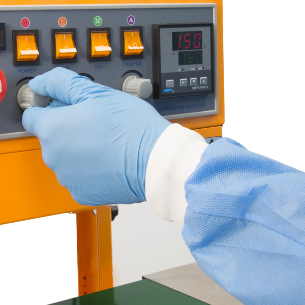 operador con guantes azules ajustando el dial en el panel de control de la selladora continua de banda JORES TECHNOLOGIES®
