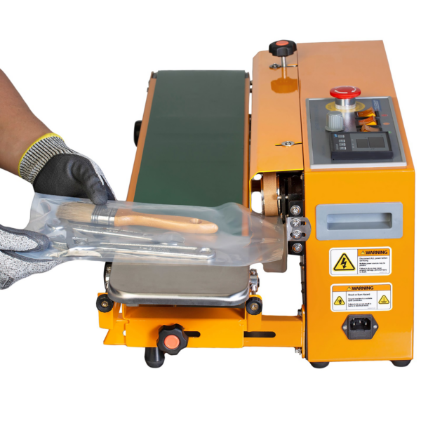 Las manos de una persona operando la selladora horizontal continua de banda JORES TECHNOLOGIES®. El trabajador está sellando una bolsa termosellable con varias herramientas en su interior.