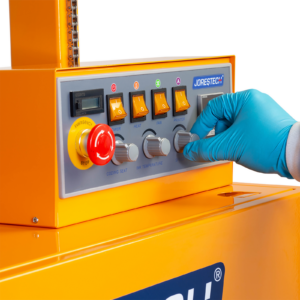 operador con guantes desechables azules ajustando el control de velocidad en un botón gris del panel de control de la selladora continua vertical de banda JORES TECHNOLOGIES® para bolsas grandes con codificador.