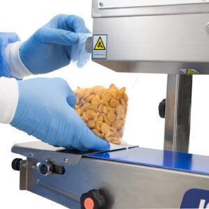 operario con guantes azules insertando una bolsa de plástico con galletas saladas en forma de pez de color naranja