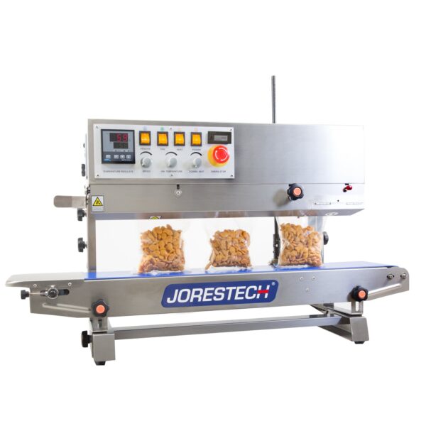 Selladora continua de banda de acero inoxidable JORES TECHNOLOGIES® de izquierda a derecha con control digital de temperatura y codificador, sellando y codificando varias bolsas de plástico transparente llenas de galletas saladas naranjas en posición vertical