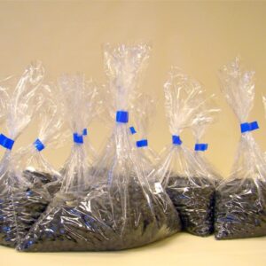 Varias bolsas de plástico transparente llenas de frijoles negros selladas con cinta adhesiva azul usando una selladora manual de bolsas