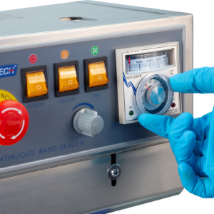 primer plano de un operador con guantes azules ajustando la temperatura en el dial analógico de la selladora continua de bolsas JORES TECHNOLOGIES®