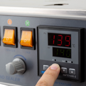 Un operario ajustando la temperatura de sellado en el panel digital de una selladora continua de banda JORES TECHNOLOGIES® para sellar bolsas.