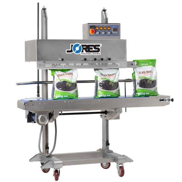 Selladora continua vertical de banda JORES TECHNOLOGIES® de acero inoxidable con codificador, logotipo azul de JORESTECH y botón de parada de emergencia rojo, sellando una producción de bolsas plásticas grandes llenas de frijoles negros