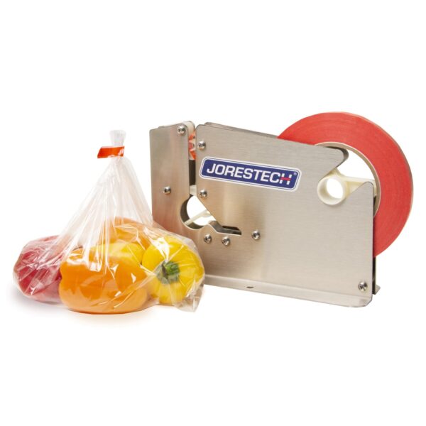Un sellador manual de bolsas de acero inoxidable con rollo de cinta roja, junto a una bolsa plástica sellada llena de pimientos morrones rojos, naranjas y amarillos.