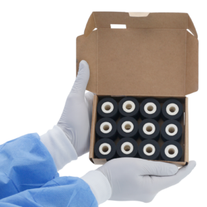 Una persona sosteniendo una caja abierta con 24 rollos de tinta caliente DAX negros de 16 mm en su interior