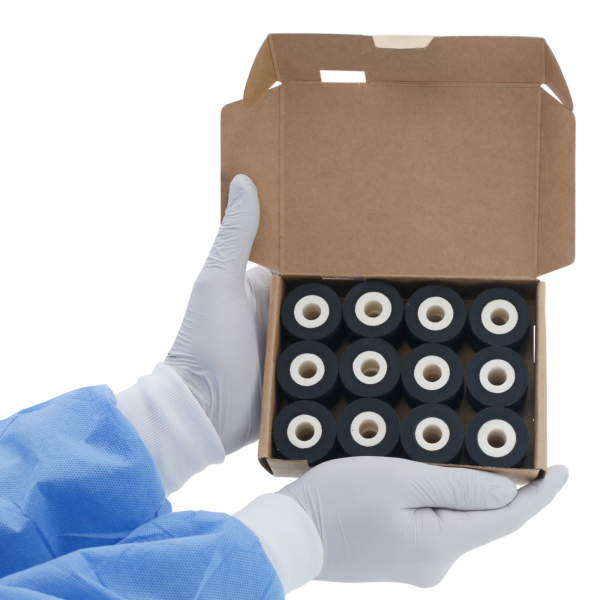 Una persona sosteniendo una caja abierta con 24 rollos de tinta caliente DAX negros de 16 mm en su interior