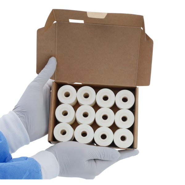 Una persona sosteniendo una caja de cartón abierta con 24 rollos de tinta caliente DAX blancos de 16 mm en el interior.