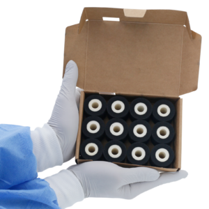Una persona sosteniendo una caja de cartón abierta con 12 rollos de tinta caliente DAX negros de 32 mm en el interior.