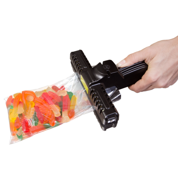 La mano de una persona con una selladora ancha manual de crimpado de calor constante de 6 pulgadas sellando una bolsa llena de caramelos