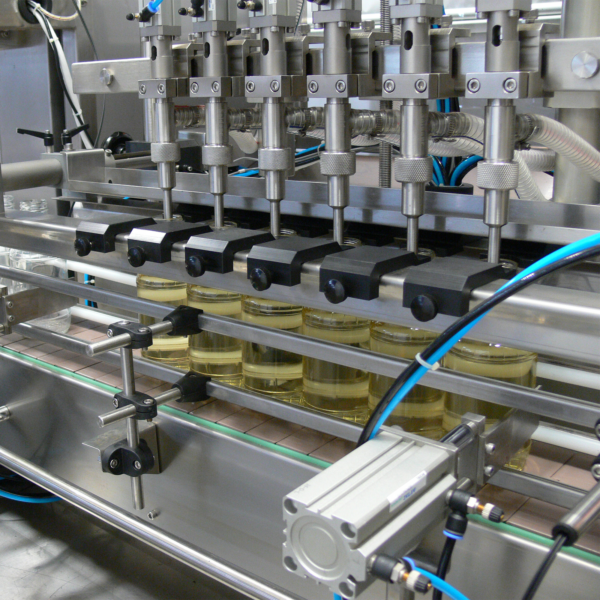 primer plano de las 6 cabezales de la máquina dispensando líquido en 6 recipientes transparentes