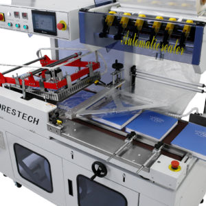 Selladora automática de film en L en producción. Hay 4 libros grandes colocados sobre la cinta transportadora motorizada mientras se sellan con plástico transparente. El panel de control digital de la selladora automática de bolsas en L está encendido.