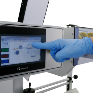 Mano de una persona tocando el panel táctil del JORES TECHNOLOGIES® Automatic L Bar Film Sealer para configurarlo antes de iniciar la producción.