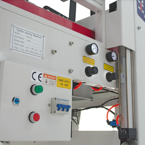 Primer plano del panel de control de una máquina selladora automática de cajas con perillas de ajuste negras, luz indicadora verde de encendido y botón rojo de parada de emergencia.
