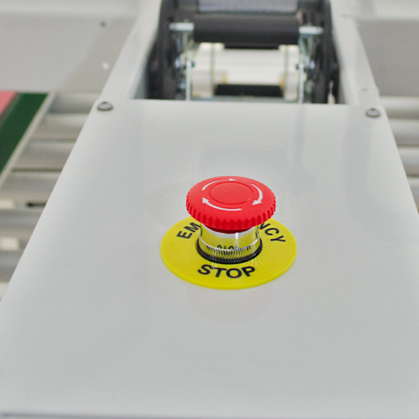 botón rojo de parada de emergencia con etiqueta amarilla en máquina selladora de cajas blanca