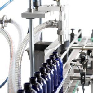 Primer plano de los dos cabezales del sistema de llenado de pasta a punto de dispensar producto de alta viscosidad en una línea de botellas azules de 1000 ml