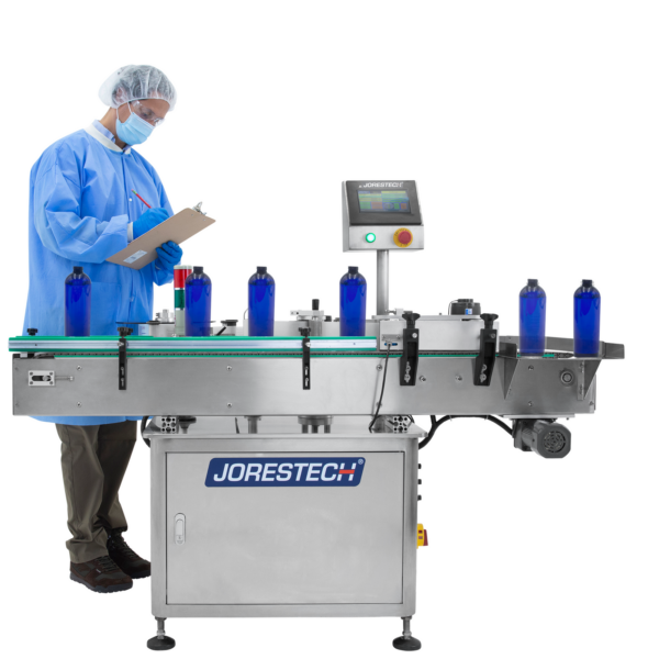 Trabajador revisando una línea de producción usando un aplicador automático de etiquetas para colocar etiquetas de producto en contenedores redondos azules.