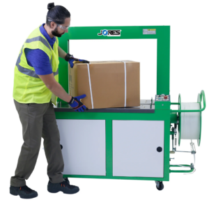 Un trabajador retirando una caja de cartón flejada de una máquina flejadora automática de polietileno JORES TECHNOLOGIES®