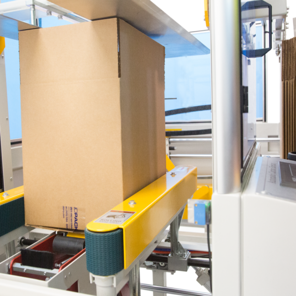 caja marrón con la parte inferior sellada con cinta transparente mientras pasa por las bandas de tracción verdes de la formadora de cajas JORES TECHNOLOGIES®