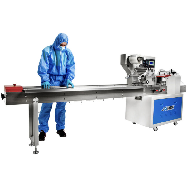 Operador vestido con un traje EPP completo azul se ve colocando productos en el transportador de cadena de una máquina de envasado flow pack horizontal