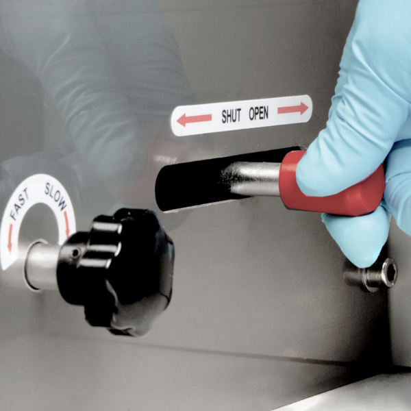 Primer plano de un operador con un guante de EPP azul operando una máquina horizontal de flow pack