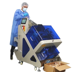 Un operario dosificando anacardos en la envolvedora de flujo inclinada automática JORES TECHNOLOGIES®. Hay una caja de cartón marrón en el suelo con producto empaquetado en bolsas individuales saliendo de la envolvedora