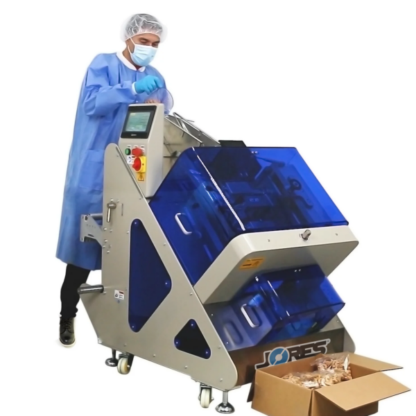 Un operario dosificando anacardos en la envolvedora de flujo inclinada automática JORES TECHNOLOGIES®. Hay una caja de cartón marrón en el suelo con producto empaquetado en bolsas individuales saliendo de la envolvedora