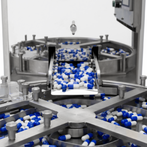 Cómo las pastillas salen de una gran tolva de acero inoxidable del contador de pastillas JORES TECHNOLOGIES® y caen en una bandeja circular segmentada.