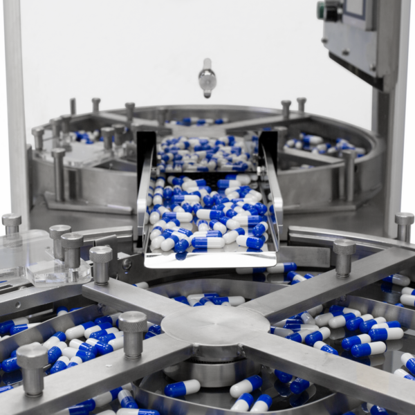 Cómo las pastillas salen de una gran tolva de acero inoxidable del contador de pastillas JORES TECHNOLOGIES® y caen en una bandeja circular segmentada.