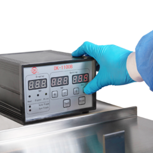 Operador con un guante desechable de EPP azul operando una máquina horizontal HFFS de flow pack. Se muestra el panel de control mientras presiona un botón para realizar ajustes al modo de funcionamiento de la máquina.