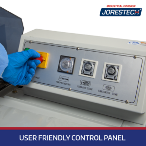 Primer plano detallado del panel de control de una Máquina Envolvedora Retráctil tipo cámara JORES TECHNOLOGIES®. Una mano con un guante azul está accionando el interruptor ON / OFF. El panel de control muestra perillas giratorias para control de temperatura, tiempo de sellado y tiempo de retractilado. Una franja azul en la parte inferior con letras blancas dice User Friendly Control Panel.