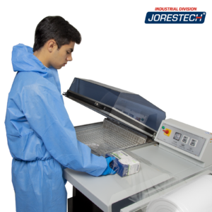 Persona con ropa de protección personal y guantes de nitrilo azules utilizando un sistema integral de embalaje termorretráctil para empaquetar una caja.