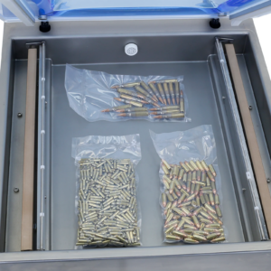 El interior de la cámara de la selladora al vacío Jorestech y las 2 barras de sellado. Dentro de la cámara hay 3 bolsas con artículos metálicos completamente envasados al vacío para evitar la exposición a la intemperie y la oxidación. Los metales generalmente se envasan al vacío para protegerlos de la oxidación.