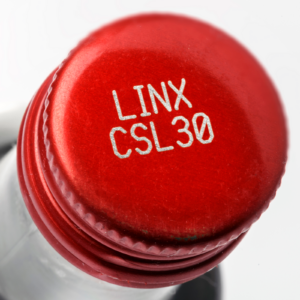 Botella de vidrio transparente con tapa metálica roja marcada con un código realizado con un codificador láser CSL30