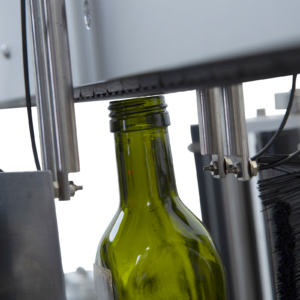 primer plano de una botella de vidrio verde dentro del aplicador automático doble de etiquetas JORES TECHNOLOGIES®