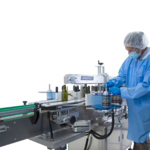 hombre con cubrecabello y cubierta protectora azules ajustando una perilla mientras sostiene el rollo de etiquetas en la aplicadora automática doble de etiquetas de acero inoxidable JORES TECHNOLOGIES® para envases redondos y planos. Botellas planas de vidrio verde están colocadas en el transportador integrado de la etiquetadora
