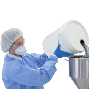 Un trabajador vestido con EPP y guantes de nitrilo llenando la tolva de una llenadora de pasta de alta viscosidad de sobremesa con pistón de JORES TECHNOLOGIES®