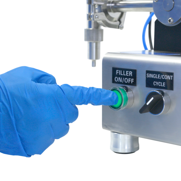 Primer plano de una persona con guantes de nitrilo azules presionando el interruptor de encendido/apagado del llenador de pistón de mesa para pasta JORES TECHNOLOGIES®