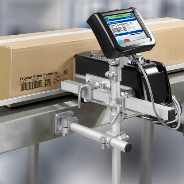 Codificador de cajas por inyección de tinta Linx IJ375 instalado en su base y base fijada a una cinta transportadora motorizada con cajas de cartón pasando por el cabezal de impresión