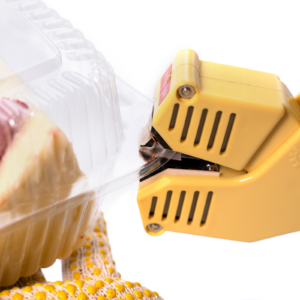 Primer plano de la mordaza de la selladora de clamshell sellando una caja transparente llena de alimentos.