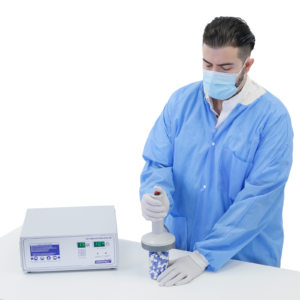 Persona en un laboratorio usando equipo de protección personal sellando un frasco de pastillas con la selladora por inducción Jorestech para tapas