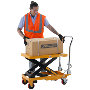 Un hombre que lleva un chaleco de seguridad naranja está retirando una caja pesada de la mesa elevadora a una altura cómoda porque la mesa tijera JORES TECHNOLOGIES® para 1100 libras está elevada
