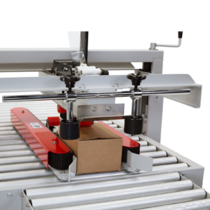 Imagen detallada de una caja siendo empujada hacia adelante por las bandas de tracción lateral en una máquina cerradora y encintadora de cajas JORES TECHNOLOGIES® CCN-110.