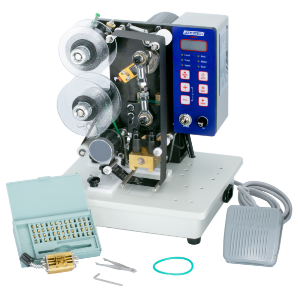Frontal de la impresora digital semiautomática JORESTECH de estampado en caliente con foil y su pedal. La máquina tiene instalado el rodillo de tinta caliente. También se muestra el juego completo de tipos, las herramientas de instalación y un portatipos incluidos con la máquina